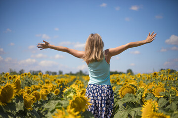 Beauty sunlit woman on yellow sunflower field Freedom and happiness concept. Happy girl outdoors