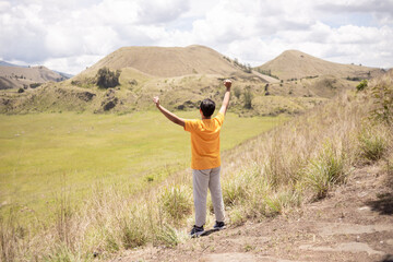 Fototapeta na wymiar Young asian backpacker man is happy and enjoy traveling in Wurung Crater (Kawah Wurung).