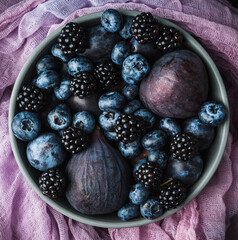 Dark berries and fruits in the bowl on the rustic background. Shot from above. Selective focus.