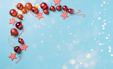 Christmas decorations red New Year's balls on ablue background with snowflakes, sparkles, confetti. Mock up holiday Christmas card copy space.