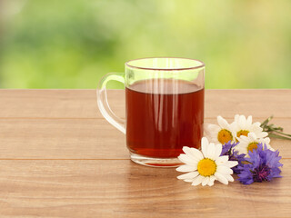 Glass cup of tea with white chamomile flowers