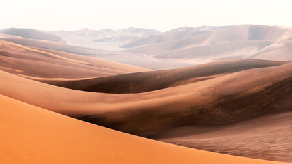 Fototapeta na wymiar Nature and landscapes of dasht e lut or sahara desert with sand dunes in foreground and hazy sky