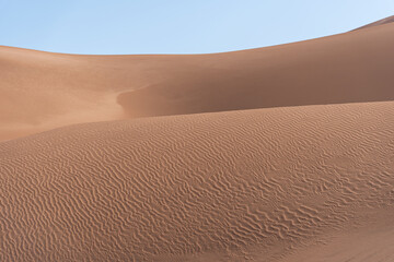 Fototapeta na wymiar the formation of sands in dasht e lut or sahara desert with waved sand pattern on sand dune. Nature and landscapes of desert. Middle East desert