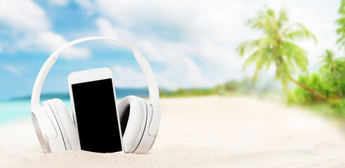 Smartphone and headphones on tropical sea beach
