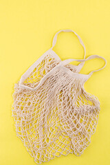 Reusable cotton and mesh eco bags for shopping on yellow background with copy space. Zero waste concept. No plastic