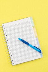 blank notebook and pen on yellow background