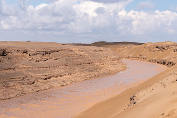 Nature and landscapes of seasonal river and valleys in dasht e lut or sahara desert with cloudy sky
