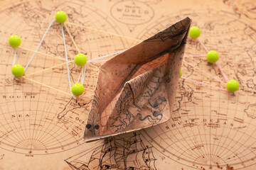 Paper boat, world map and pins, closeup