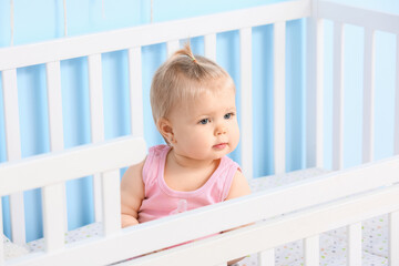 Cute baby girl in cot at home