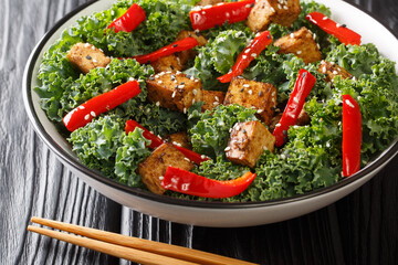 Organic vegan tofu salad with peppers, kale and sesame seeds close-up in a bowl on the table. horizontal
