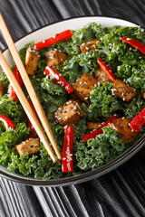Teriyaki tofu salad with peppers, kale and sesame seeds close-up in a bowl on the table. Vertical