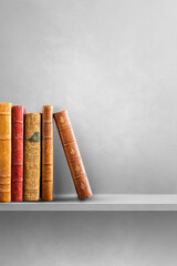 Row of old books on grey shelf. Vertical background