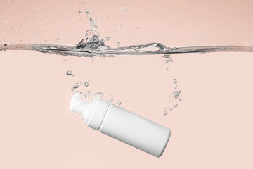 Bottle of cosmetic product in water with splashes on color background - obrazy, fototapety, plakaty