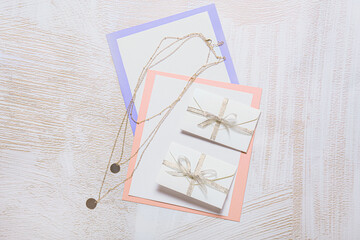 Cards with envelopes and necklace on white background
