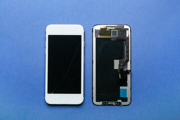 Mobile phone with damaged screen and display module on blue background