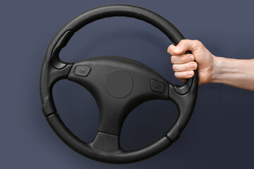 Man holding modern steering wheel on dark background
