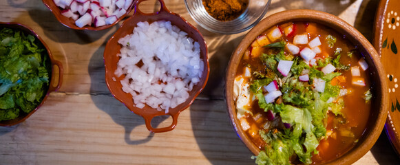 Delicious traditional Mexican pozole, tostadas, and condiments on wooden table