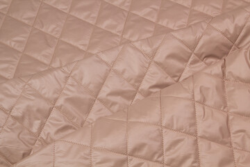 Quilted fabric. The texture of the blanket. Beige textiles