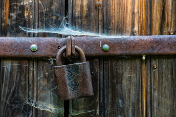 Close up view of the old rusty padlock on a aged gray wooden door