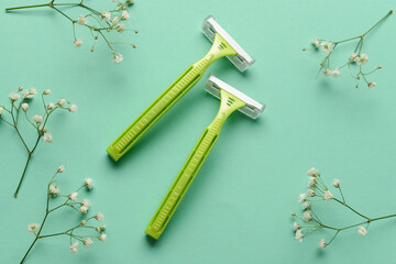 Safety razors and flowers on color background