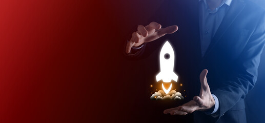 Startup business concept, Businessman holding tablet and icon rocket is launching and soar flying out from screen with network connection on dark background.