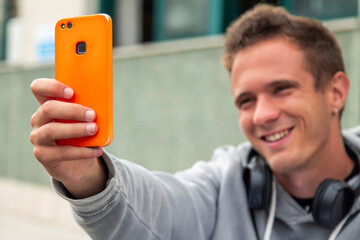 young man with headphones taking a selfie with the smartphone