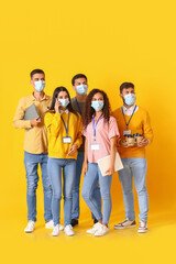 Team of young business people in medical masks on yellow background