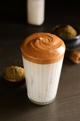 Glass of tasty dalgona hojicha latte on dark wooden background