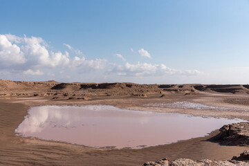 Fototapeta na wymiar gathered water in a arid lake in dasht e lut or sahara desert with cloudy sky