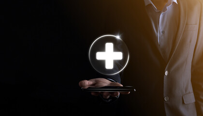 Obraz premium Businessman hold virtual plus medical network connection icons. Covid-19 pandemic develop people awareness and spread attention on their healthcare.