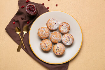 Plate with tasty cranberry muffins on color background