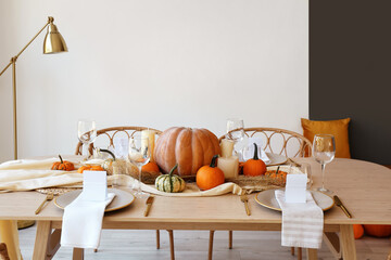Dining table with pumpkins near light wall