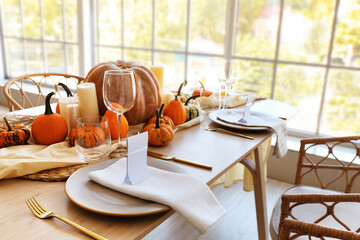 Beautiful autumn table setting with pumpkins in room