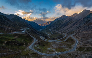 Aerial landscape from top of mountain peak, curved asphalt serpentine road to top. Beautiful panorama before sunset, golden hour. Mountains of Sichuan, China. Way to the top.
