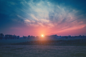 Rural landscape at sunset. Silhouette of the village against the background of a beautiful gradient evening sky