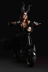 Fototapeta na wymiar Woman dressed for Halloween with motorcycle on dark background