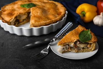 Baking dish and plate with piece of tasty chicken pot pie on black background