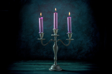 Candle magic. Burning candles in a vintage candle holder on a dark background, toned image