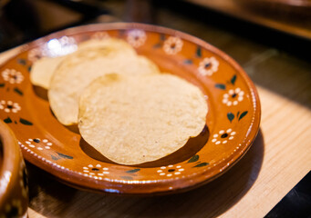 Three traditional Mexican tostada shells on a handmade clay plate