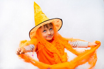 boy in halloween costume, orange witch hat, cobwebs and spiders.