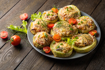 Zucchini stuffed with meat and rice with tomatoes, dill, lettuce on a round plate. 