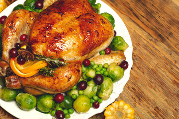 Thanksgiving turkey or chicken for a festive dinner. Food table background with autumn seasonal specialties for Thanksgiving Day. Fried chicken with pumpkin, vegetables and autumn decor on a wooden