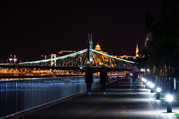 Obraz premium Budapest at night, two people walk along the Danube embankment.