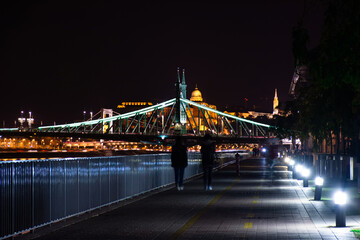 Budapest at night, two people walk along the Danube embankment.