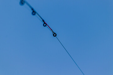 Stretched fishing line close-up. Fishing rod against the sky. Seasonal fishing. High quality photo