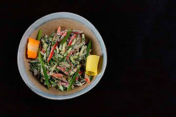 Top view of salad with vegetables, chicken and mayo on a black background