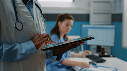 Close up of african american doctor using tablet with touch screen for healthcare information in...