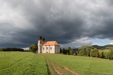 Church of St. Margaret from the 18th century near &Scaron;onov. Beautiful church chapel in middle of fields in czech countryside broumovsko region with hills of broumov walls on background. Czech landscape.