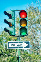 Double traffic light with one way street sign on a sunny day.