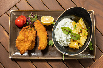 Fried chicken breasts served with potatoes and salad